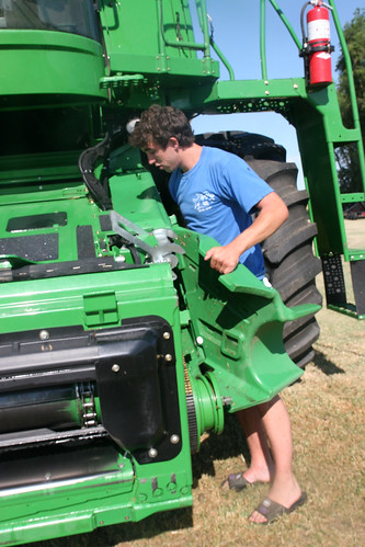 Oak replaces a feeder house cover after the combine has been washed.