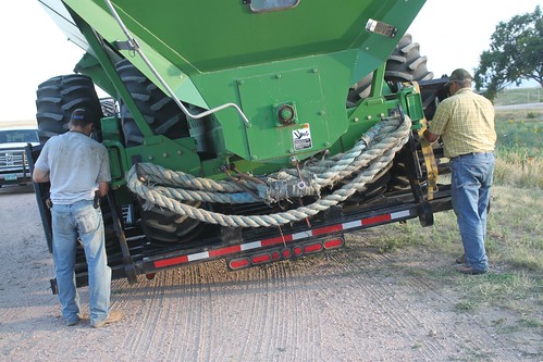 Dad and Brandon tightening the straps on the grain cart trailer.