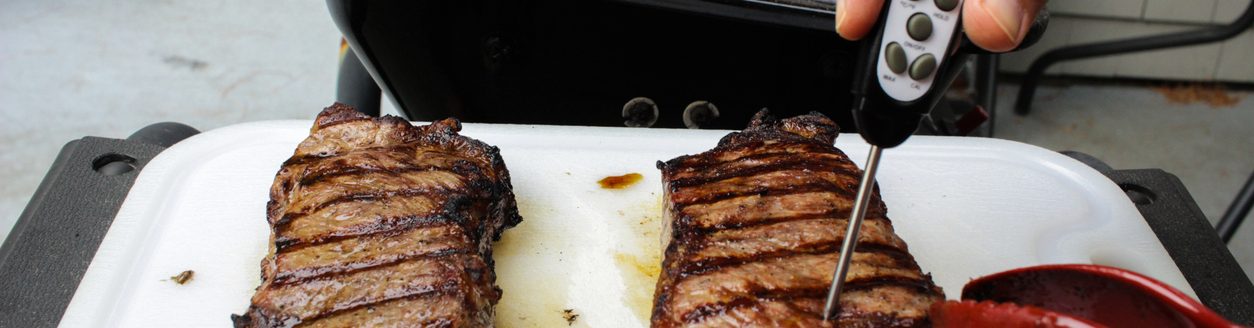 After pulling steaks off a barbecue grill, a digital thermometer is used to test how well the meat has been cooked. (Adobe Stock │ #610114824 - unrestedm)