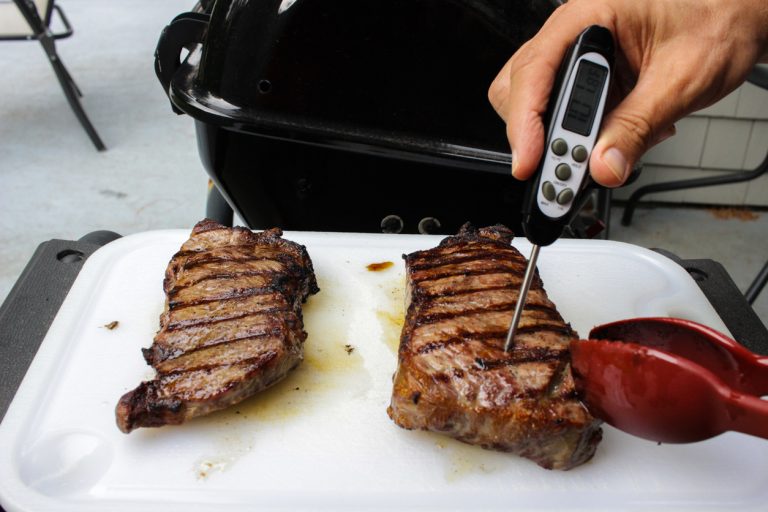 After pulling steaks off a barbecue grill, a digital thermometer is used to test how well the meat has been cooked. (Adobe Stock │ #610114824 - unrestedm)