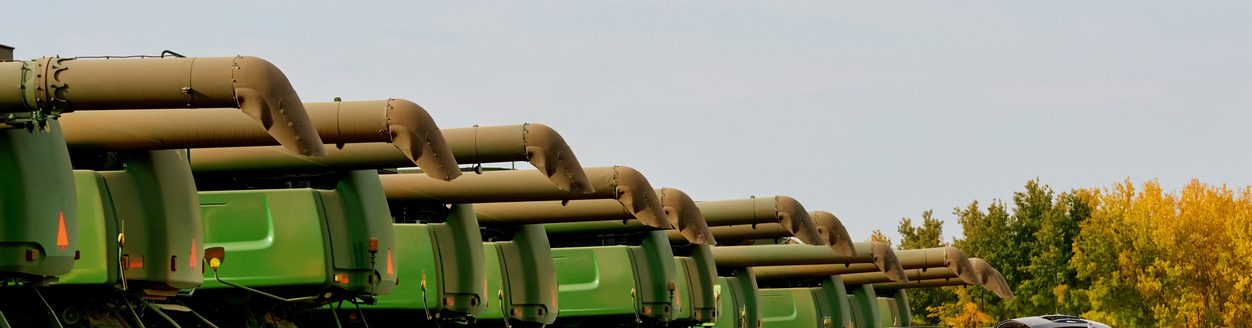 Many combine harvester machines in a row on agriculture farm with woman standing by her car and taking out some stuff. (iStock │ #1895288797 - AJ_Watt)
