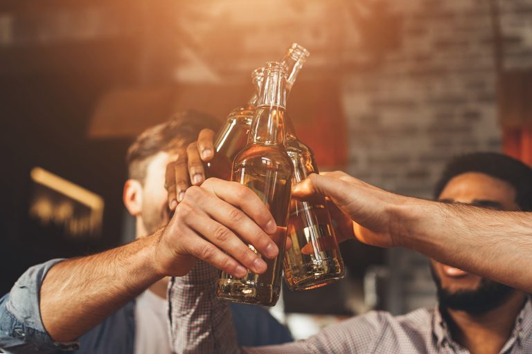 Men Drinking Beer And Clinking Bottles At Bar. (Adobe Stock │ #269059411 - Prostock-studio)
