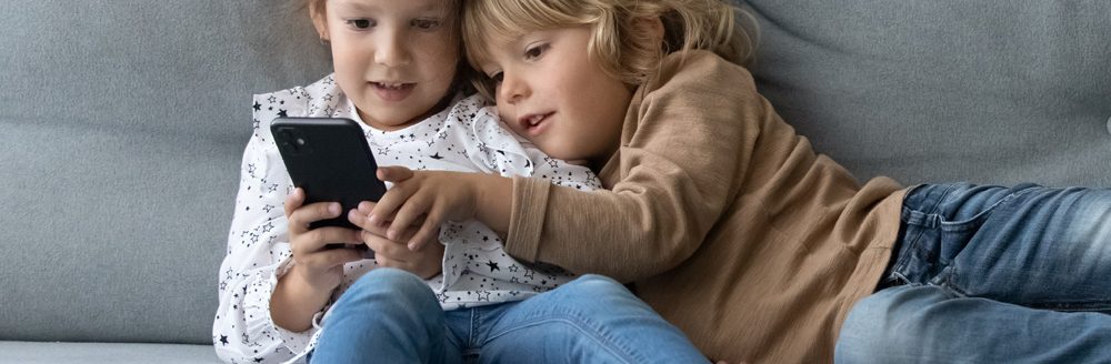 Kids looking at smartphone screen, enjoying spending time online playing video games. (Adobe Stock │ #489677909 - fizkes)