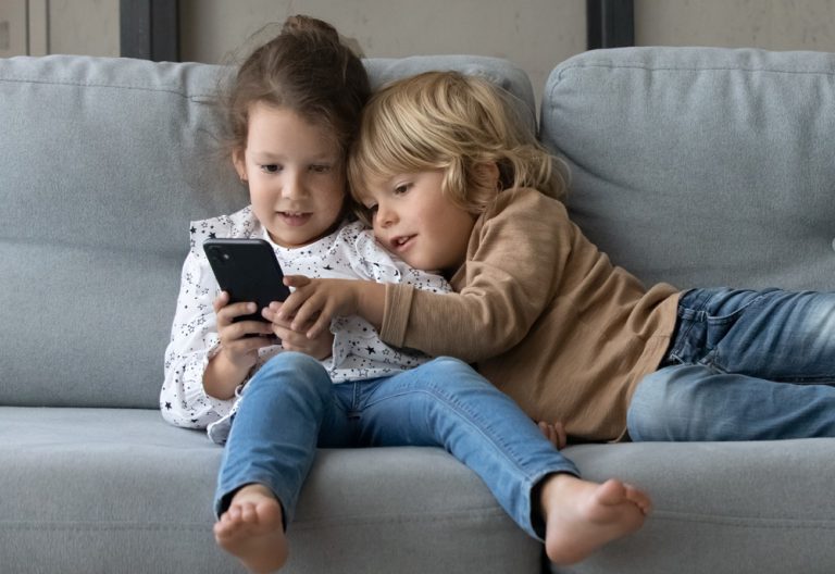 Kids looking at smartphone screen, enjoying spending time online playing video games. (Adobe Stock │ #489677909 - fizkes)