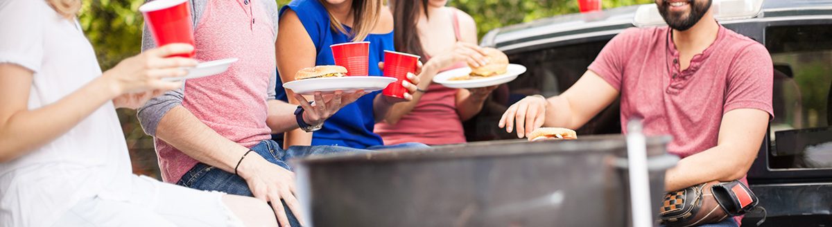 People eating hamburgers next to a grill. (Adobe Stock │ #114798290 - AntonioDiaz)