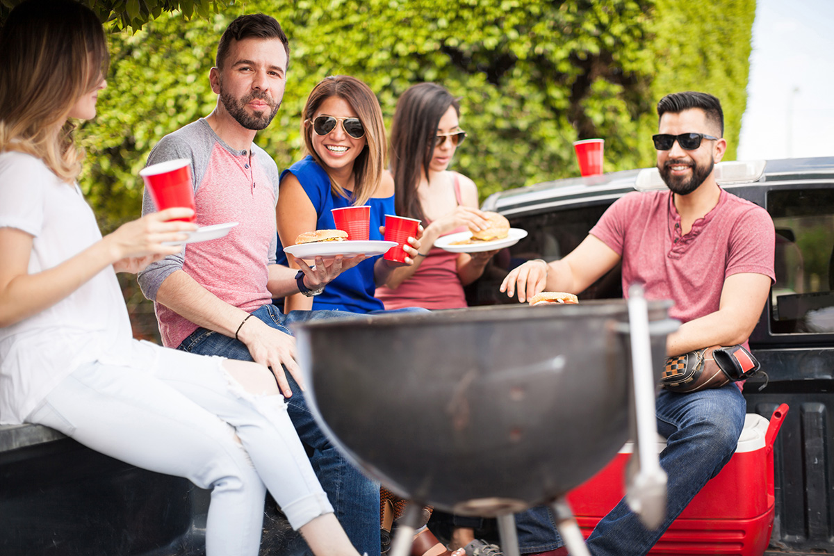 People eating hamburgers next to a grill. (Adobe Stock │ #114798290 - AntonioDiaz)