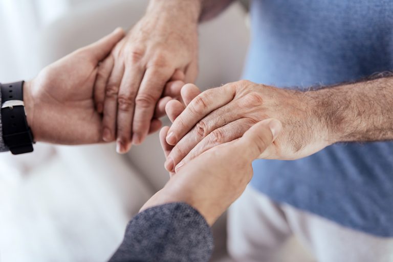 Close up of attractive male hands squeezing old male hands. (Adobe Stock │ #211673969 - Viacheslav Yakobchuk)
