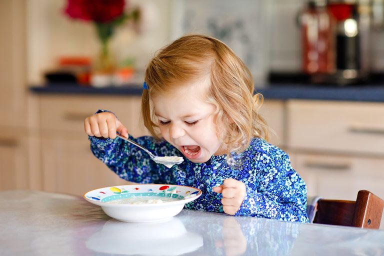 Adorable toddler girl eating healthy cereal with milk for breakfast. (Adobe Stock │ #280012267 - Irina Schmidt)
