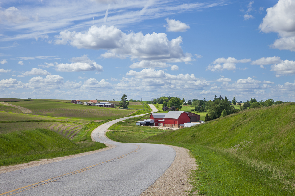 Farm with a red barn on a curving road in the Iowa countryside on a beautiful spring day. (iStock │ #2157489040 - Willard)