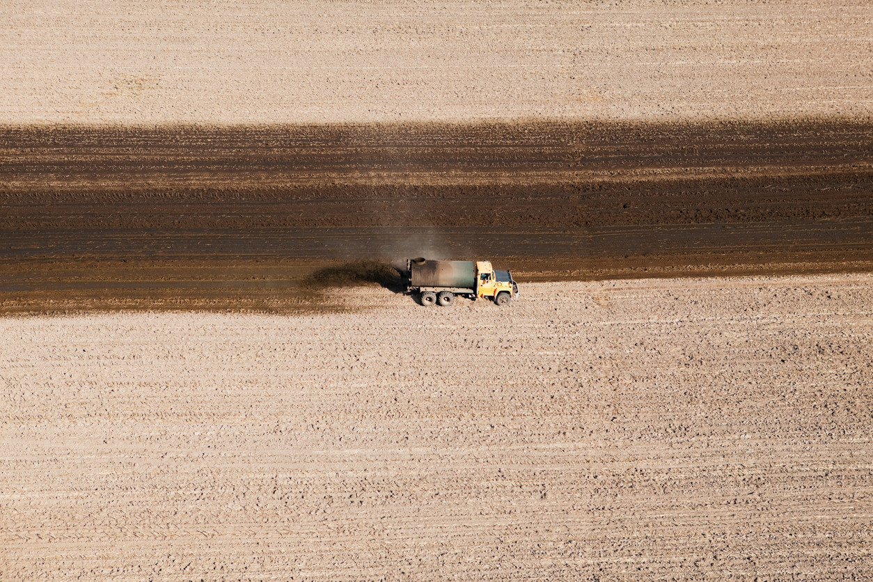 Aerial view of a tank truck spreading manure on a recently harvested corn field. (iStock │ #181878441 - BanksPhotos)