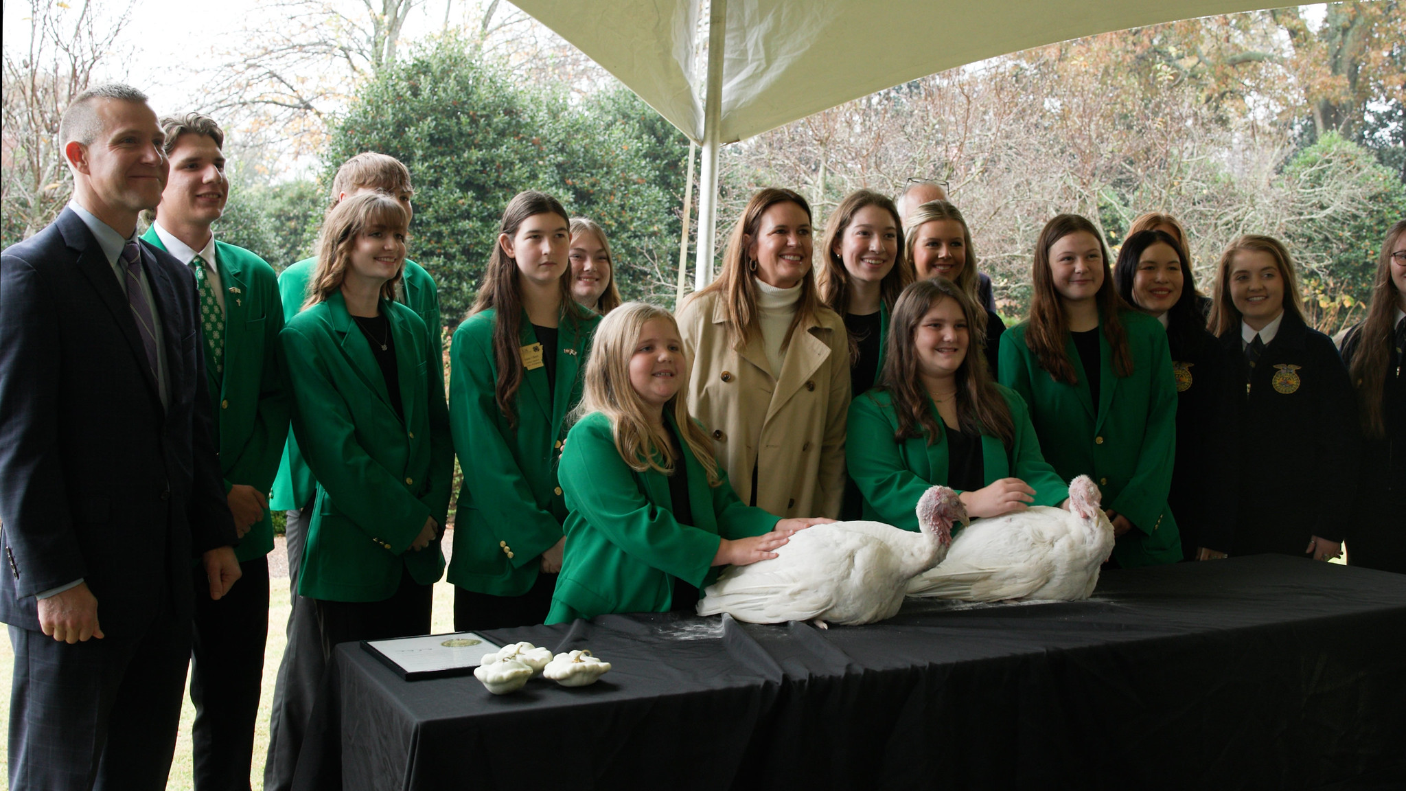 Arkansas Gov. Sarah Huckabee Sanders (center) poses for a photo with 4-H members Adeline Dixon and Caroline Dixon (front) who raised the turkeys that Sanders pardoned on Nov. 20, 2025, during a ceremony at the Governor's Mansion in Little Rock. With them are from left: Arkansas Agriculture Secretary Wes Ward, Arkansas 4-H State Officers team members, and FFA members. UADA photo / Ben Aaron