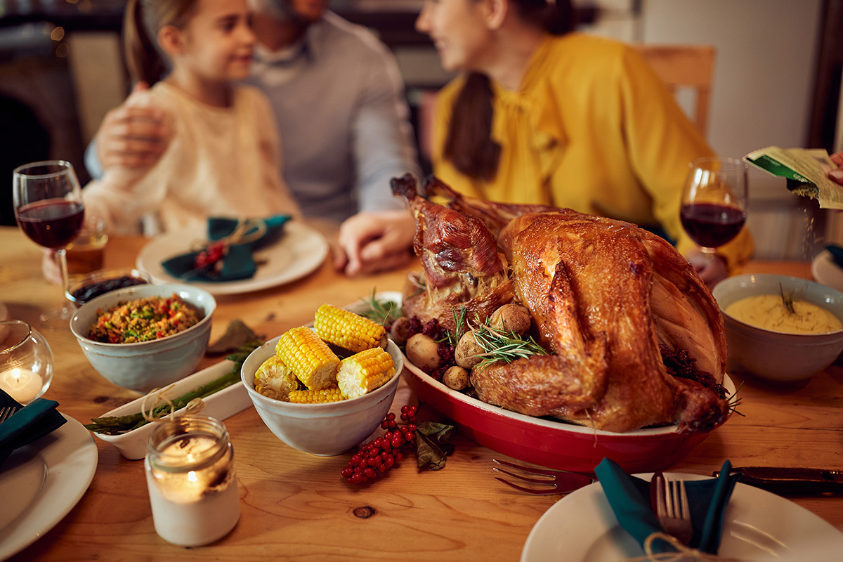 Close-up of Thanksgiving turkey during family dinner at dining table. (Adobe Stock │ #454595209 - Drazen)