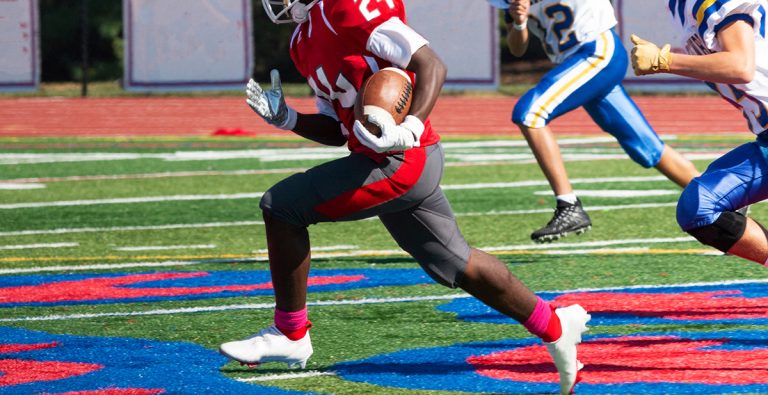 Football running back being chased by defensive players down the field. (Adobe Stock │ #484994733 - coachwood)