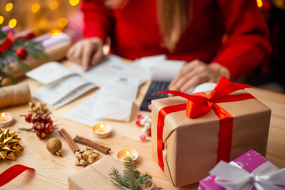 Table full of bills, hands of a woman, who checks and calculates everything. Christmas shopping concept. (Adobe Stock │ #539112708 - Vitalii)