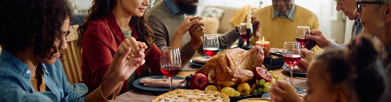 Grateful multigeneration family holding hands while praying at dining table on Thanksgiving. (iStock │ #1727472895 - Drazen Zigic)