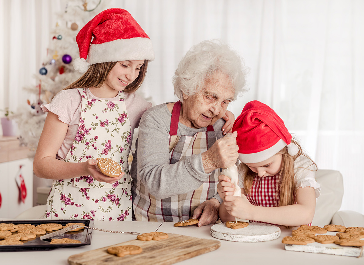 Grandmother with granddaughters decorating cookies. (Adobe Stock │ #287135617 - tan4ikk)