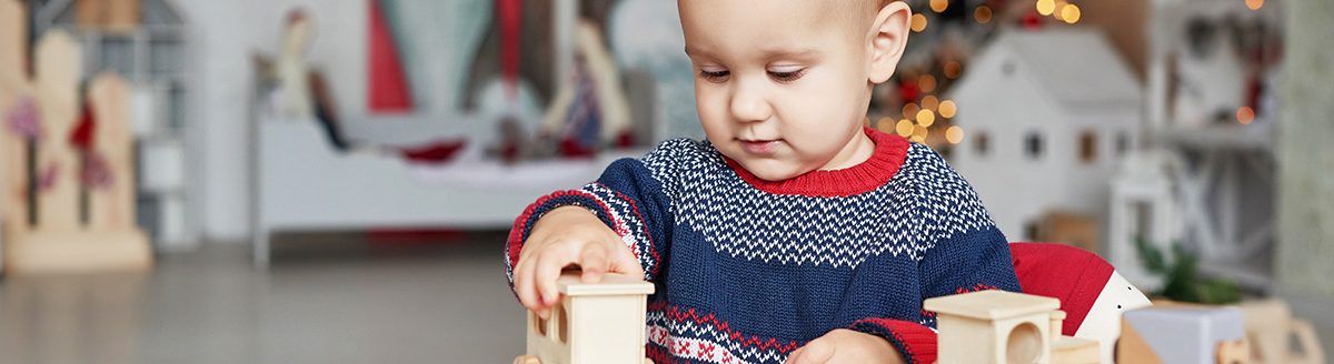 Cute little boy is playing with toy wooden train. (Adobe Stock │ #302543883 - Aleksandr)