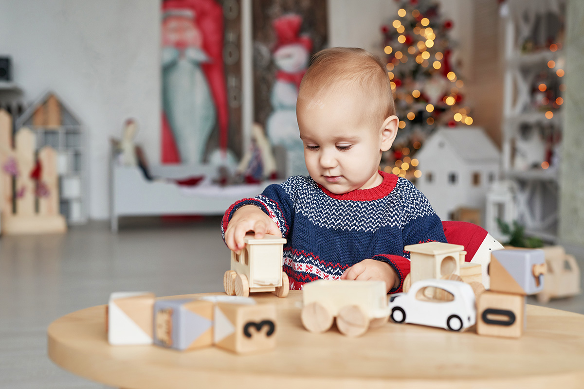 Cute little boy is playing with toy wooden train. (Adobe Stock │ #302543883 - Aleksandr)