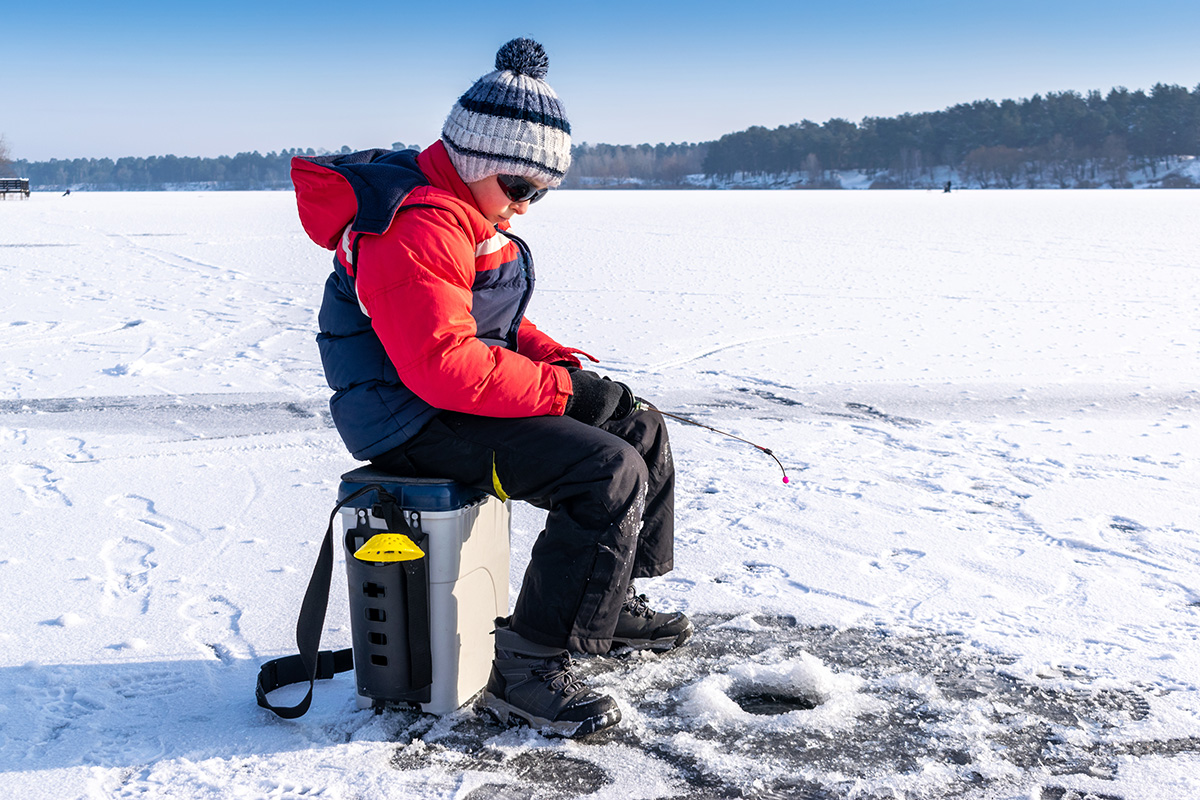 Boy enjoys winter fishing. (Adobe Stock │ #407385436 - Maksym Dragunov)