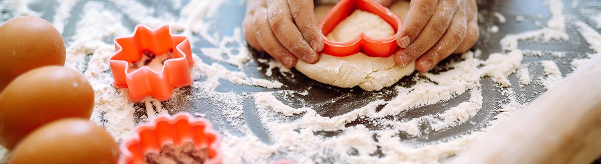 Close up of boy hands carving dough with cookie heart cutters. (Adobe Stock │ #409674758 - maxbelchenko)