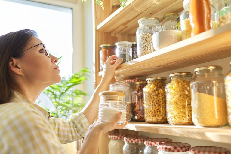 Food storage in pantry, woman holding jar of sugar in hand. (Adobe Stock │ #333994675 - Valerii Honcharuk)