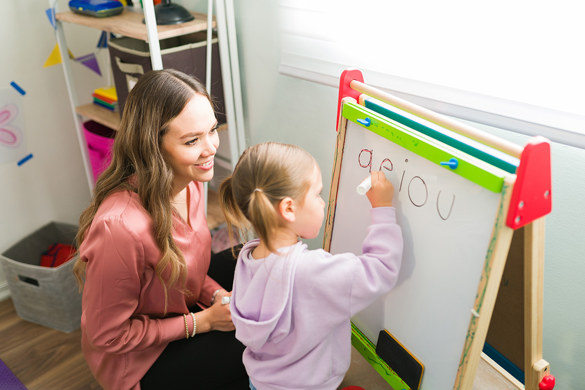 Female tutor teaching the alphabet a preschool girl. (Adobe Stock │ #415055225 - AntonioDiaz)