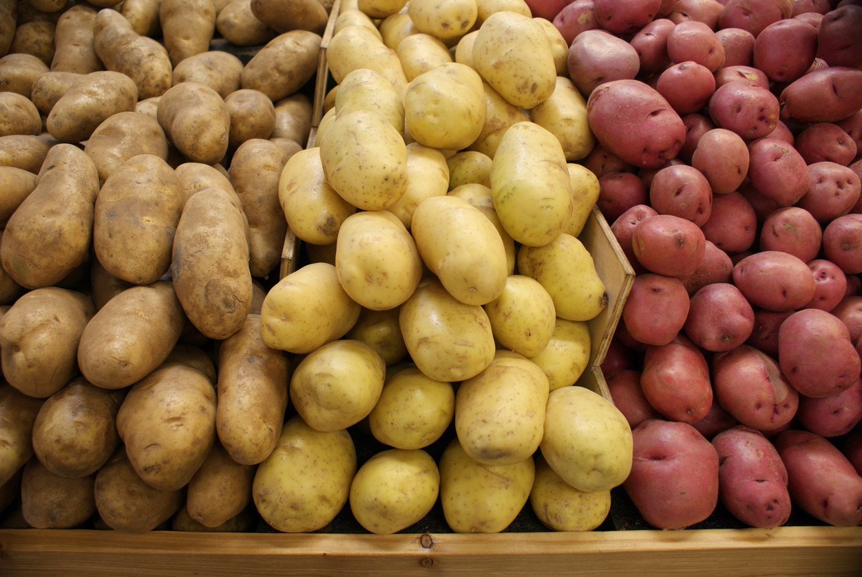 Three different kinds of potatoes, in bins at a farmer's market. (iStock │ #172937343 - TheCrimsonMonkey)