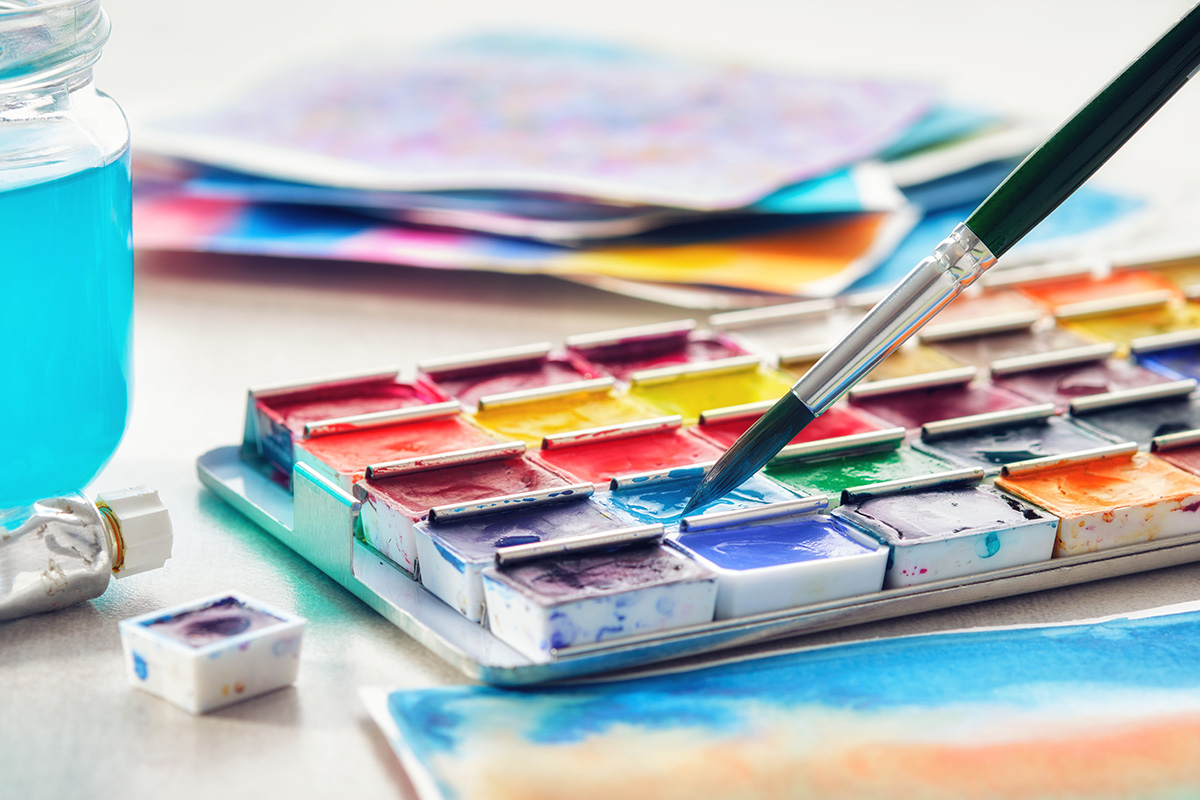 Set of watercolor paints, paintbrush, glass of water and paper sheets of watercolor paintings. (Adobe Stock │ #416175834 - chamillew)