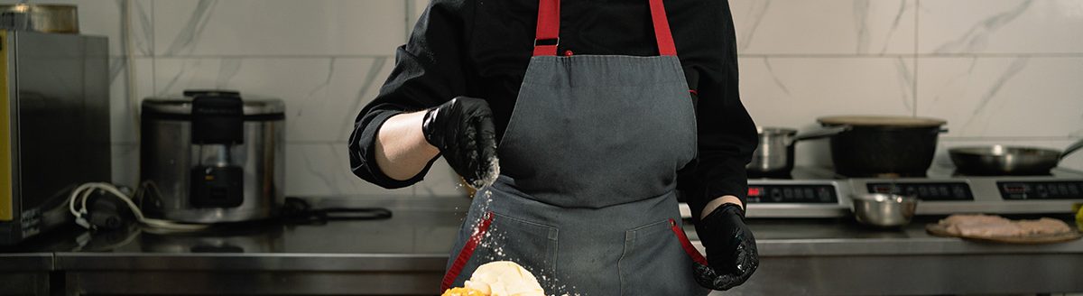 Woman chef in a restaurant in the kitchen pour salt into a large bowl of salad. (Adobe Stock │ #473985028 - Andrii Lysenko)