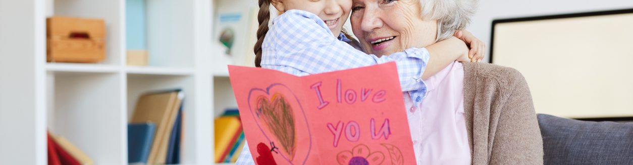 Portrait of cute little girl hugging grandma and giving her handmade I love you card on Valentines day. (iStock │ #1141513700 - SeventyFour)