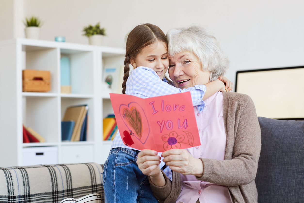 Portrait of cute little girl hugging grandma and giving her handmade I love you card on Valentines day. (iStock │ #1141513700 - SeventyFour)
