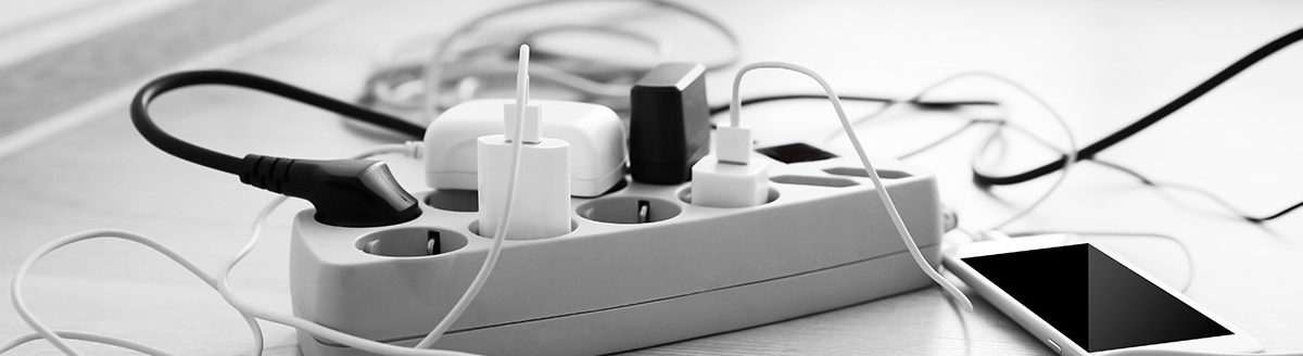 Mobile phones charging into power cord on wooden floor indoors. (Adobe Stock-#108250553 │ Africa Studio)