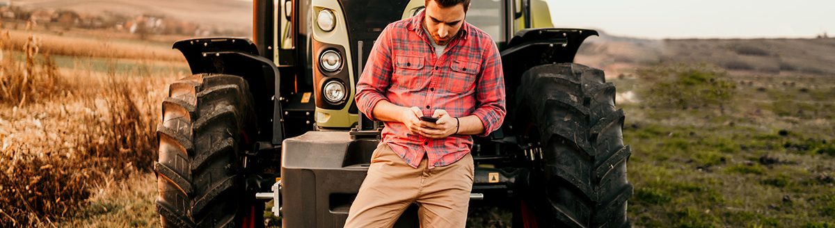 Farmer using smartphone and tractor at harvesting. (Adobe Stock │ #234551396 - aboutmomentsimages)