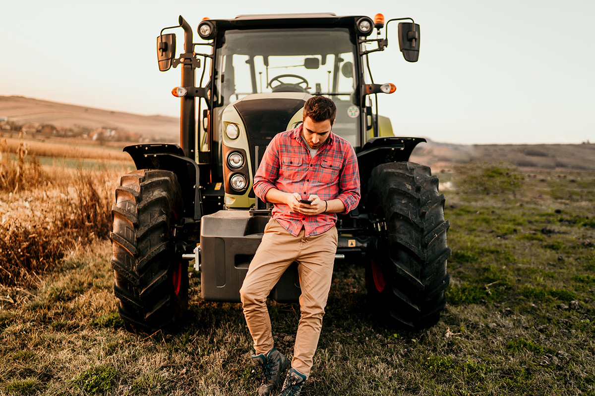 Farmer using smartphone and tractor at harvesting. (Adobe Stock │ #234551396 - aboutmomentsimages)