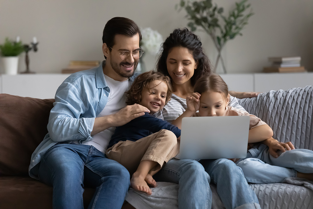 Couple with children relaxing on sofa with laptop. (Adobe Stock │ #483713030 - fizkes)