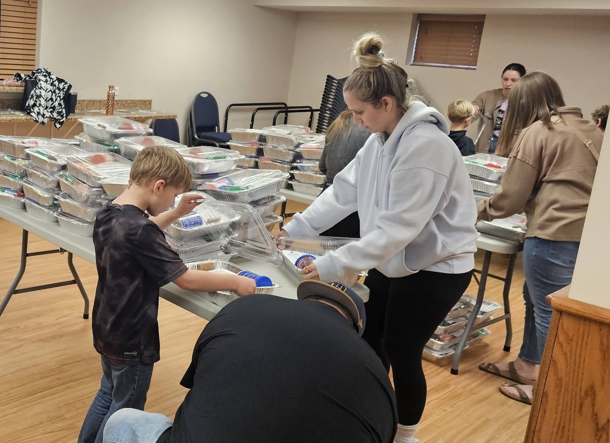 Clover Kids work alongside caring adult partners and parents in a Birthday Kit assembly line. They were completing the final step in packaging their Birthday Kits to be donated to food pantries across Poweshiek County. (Iowa State University Extension and Outreach)