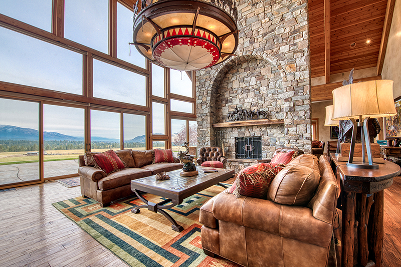 The great room features 34-foot ceilings, a large stone fireplace and an entire outer wall of floor-to-ceiling windows. (Courtesy of Hall and Hall) 