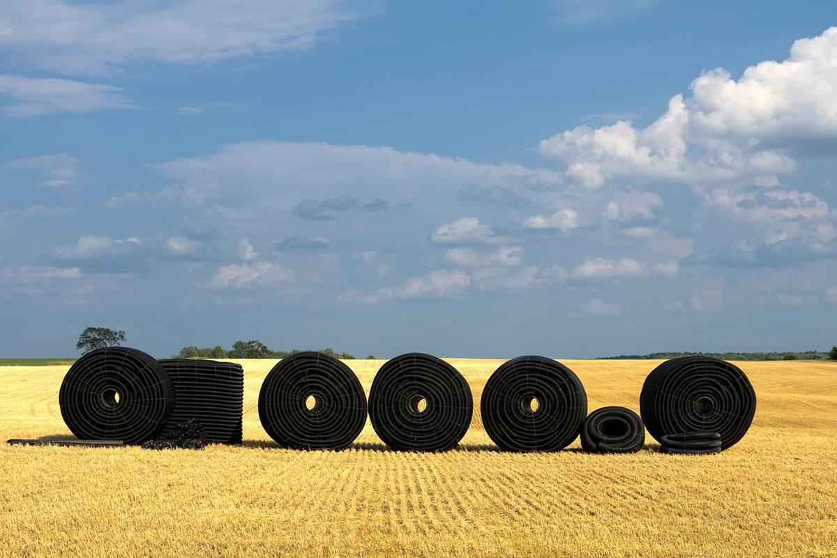 A farm field with rolls of plastic drainage tile in a row ready to be buried in the ground. (iStock-#176447321 │ SimplyCreativePhotography)