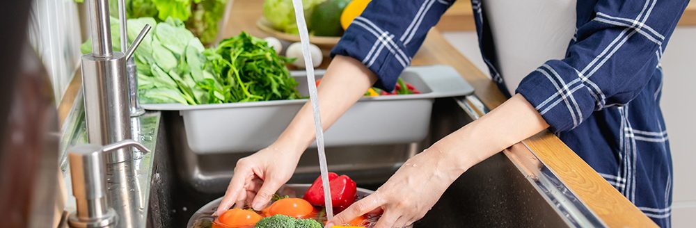 Close up woman washing vegetables above kitchen sink. (Adobe Stock-#470081576 │ khwanchai)
