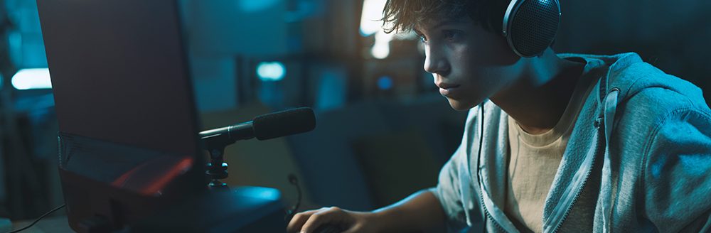 Teenager wearing headphones and playing online video games. (Adobe Stock-#478073888 │ stokkete)