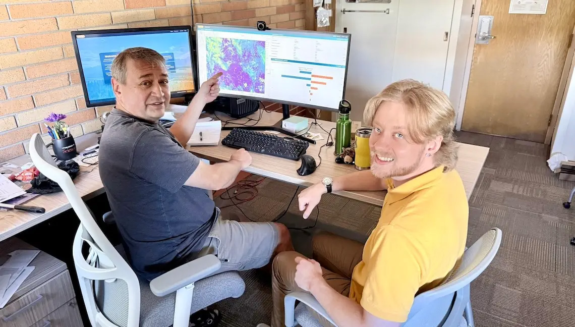 Shannon Albeke (left), senior research scientist, and Will Kirkpatrick, a geospatial developer, both with the Wyoming Geographic Information Science Center at the University of Wyoming, look over information from the new WyldFire app they helped develop. WyldFire is a new public-facing wildfire information platform designed to help Wyoming residents, landowners, public land managers, emergency services, utilities, and communities better understand wildfire risk across the state. (UW Photo)