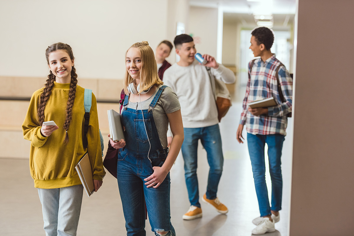 Group of happy high school classmates walking by school corridor together. (Adobe Stock-#200238277 │ LIGHTFIELD STUDIOS)