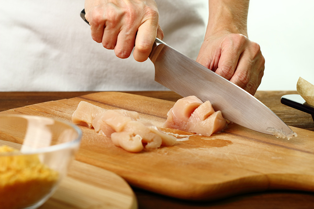 Cutting chicken fillet. (Adobe Stock-#300899613 │ ffolas)