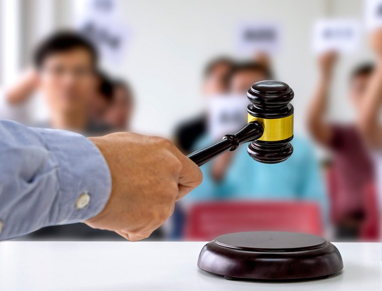 The person carrying the auction holds a wooden hammer in his hand to make a bid to sell the product. (Adobe Stock-#309197587 │ Pongsak)