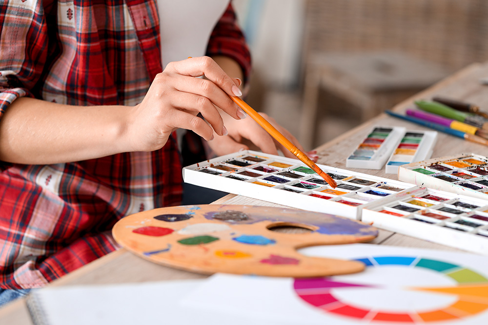 Young female artist painting in studio, closeup. (Adobe Stock-#312133268 │ Pixel-Shot)